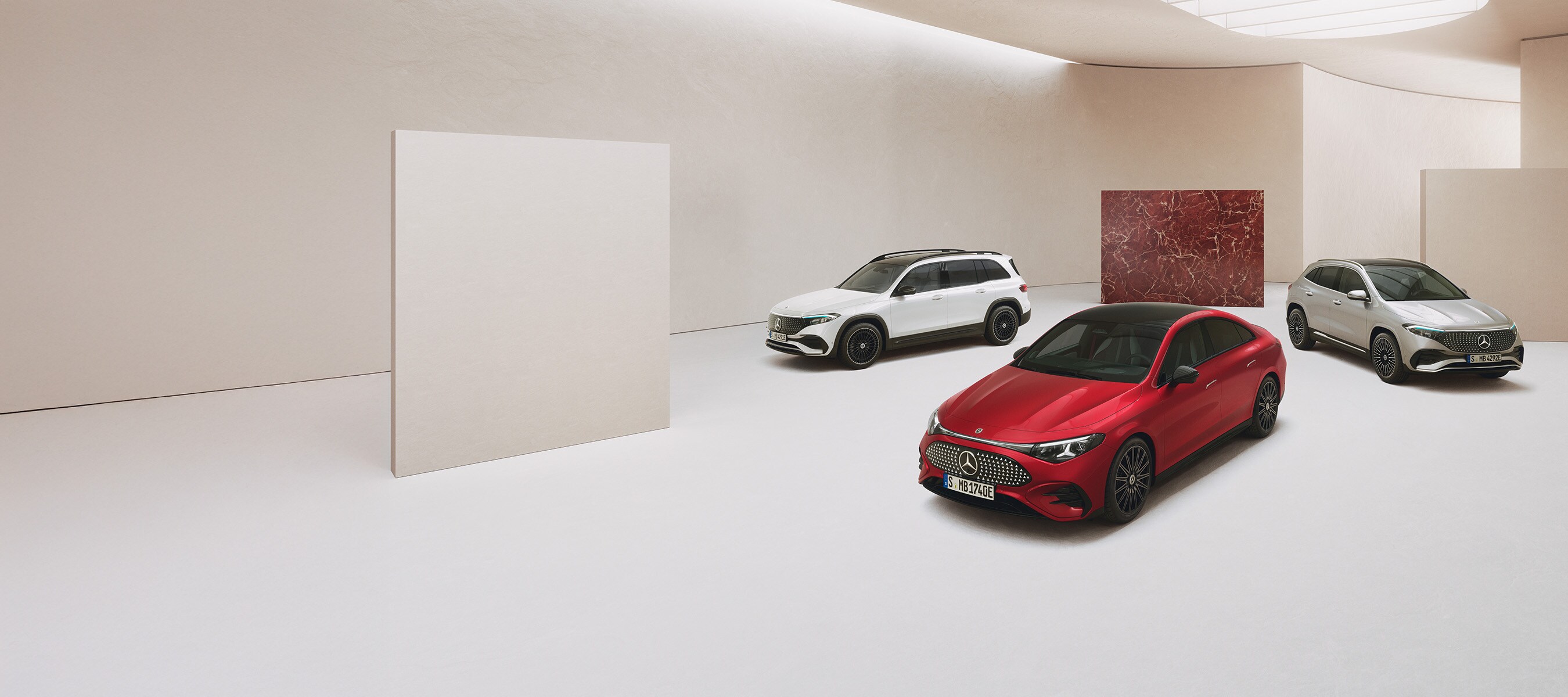 Garanti. Med lang rækkevidde | Mercedes-Benz Tre elektriske Mercedes-Benz biler holdende i et minimalistisk showroom.