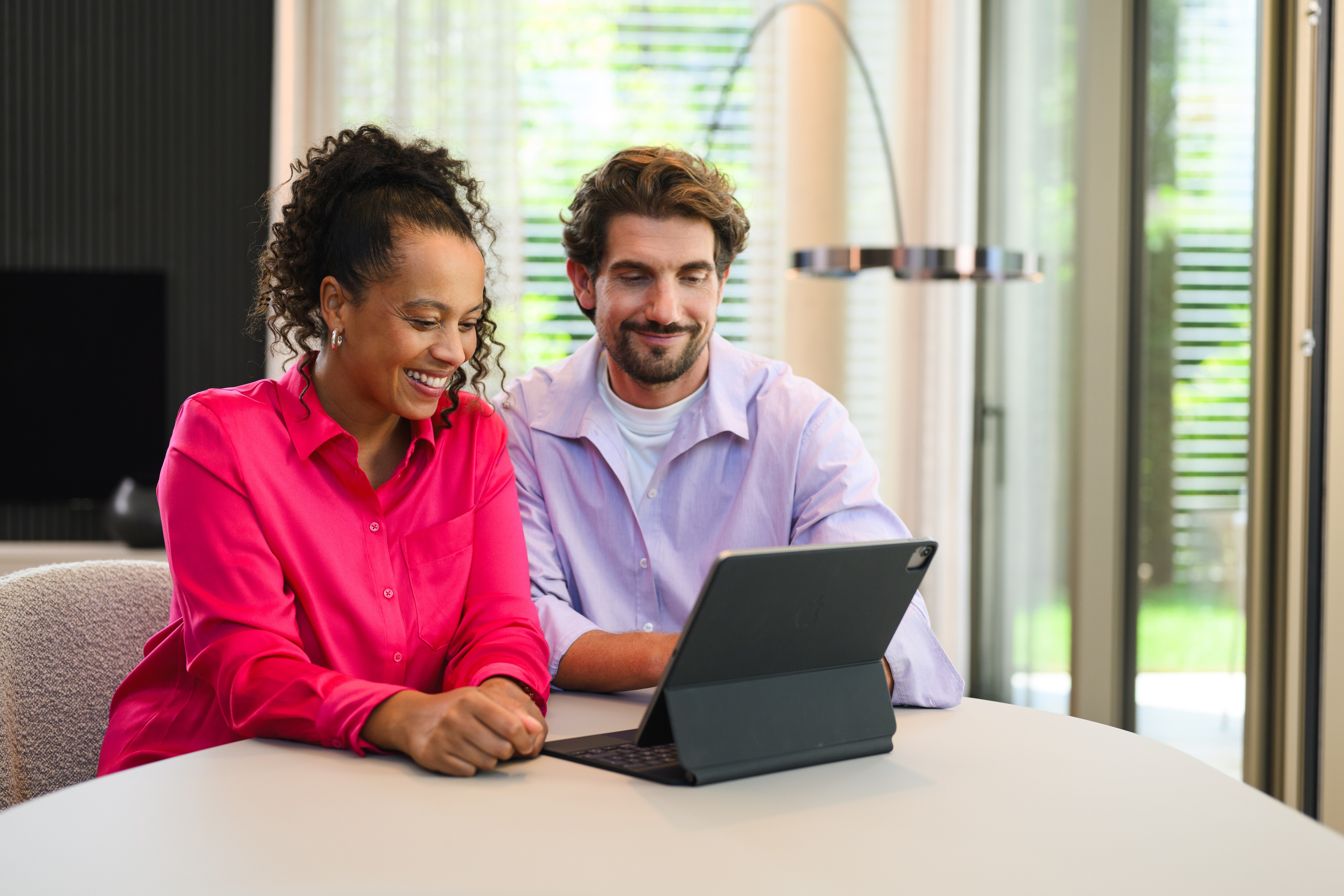 Online Showroom | Aktuelle kampagner | Mercedes-Benz Mand og kvinde sidder med en tablet og køber en Mercedes-Benz online